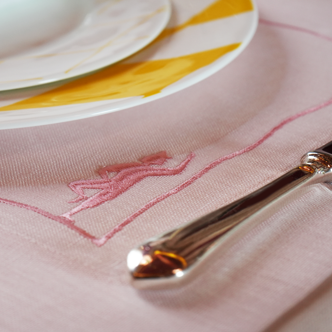 Load image into Gallery viewer, Close-up of a silver fork on a pink embroidered napkin with plates in the background.
