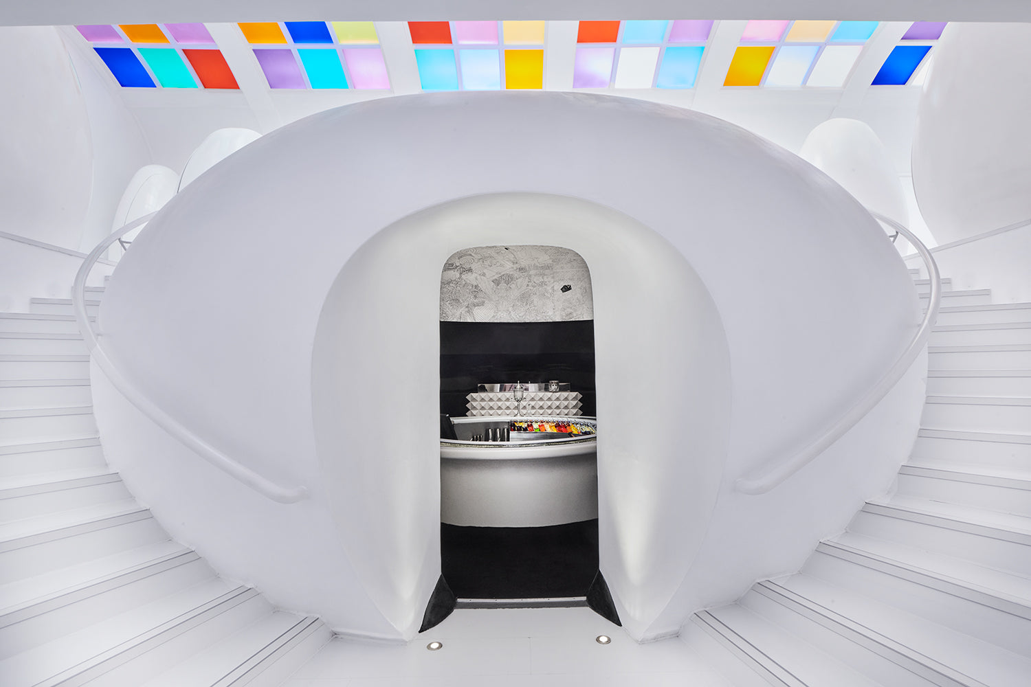 Load image into Gallery viewer, White pod with a door open, revealing a dark interior with lights, on a white floor.