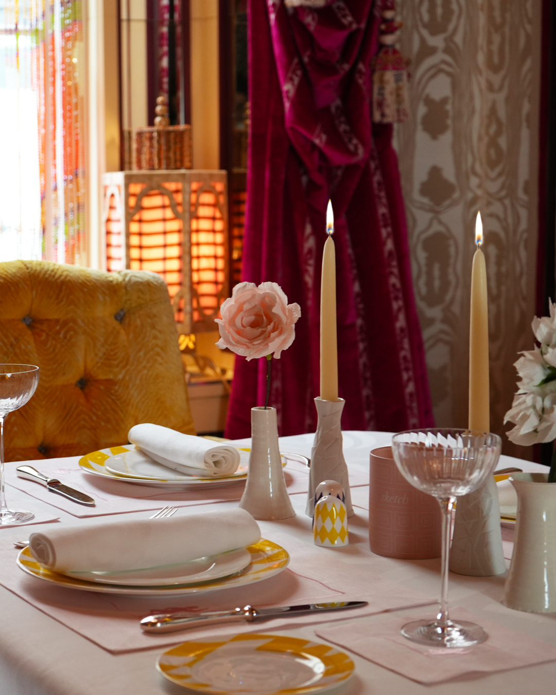 Load image into Gallery viewer, Elegant table setting with candles, flowers, and cutlery in a warm-toned room.